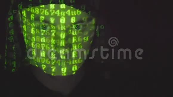 在黑暗的办公室里在引擎盖上工作的男性黑客的脸而绿色代码字符在他的脸上反射视频的预览图