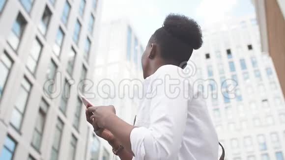 非洲妇女在户外坐在白色楼梯上使用智能手机视频的预览图