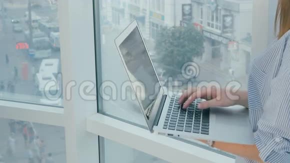 女士使用笔记本电脑附近的全景窗口在现代明亮的办公室视频的预览图