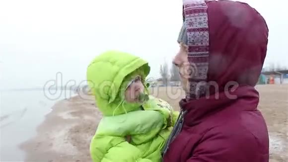 妈妈抱着一个小孩站在沙滩上视频的预览图