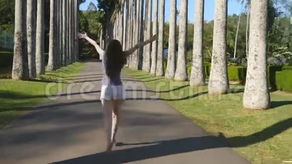 年轻美丽的女人慢跑和旋转的异国公园和乐趣快乐女孩在热带公园跑步视频的预览图