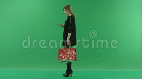 带包的年轻女子在手机上发短信彩色钥匙绿色背景视频的预览图