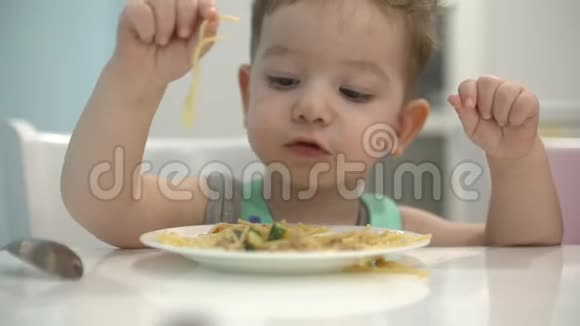 小孩子坐在围兜里的一张桌子旁吃自己的意大利面宝宝心甘情愿地吃视频的预览图