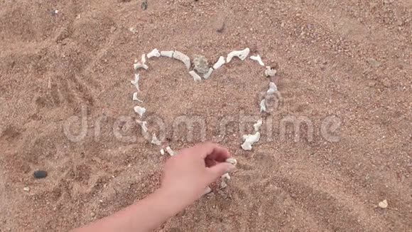 女孩把珊瑚的心放在海滩上视频的预览图