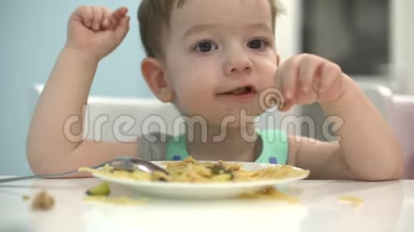 小孩子坐在围兜里的一张桌子旁吃自己的意大利面宝宝心甘情愿地吃视频的预览图