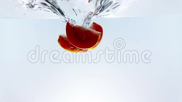 新鲜的红片番茄溅落到水里在白色背景营养和保健食品上缓慢地射击视频的预览图
