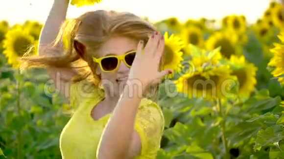 红色长发的美女站在黄色的向日葵田里户外快乐的女人少年少年面子肖像视频的预览图