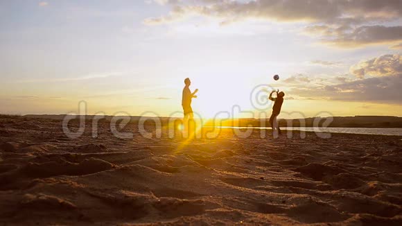 男子在阳光下的沙滩上打排球夏天的傍晚打沙滩排球视频的预览图