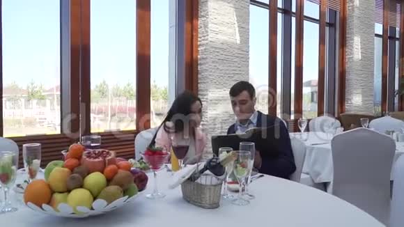 一个男人和一个女孩在一家餐馆的餐桌上探索菜单库存录像视频的预览图