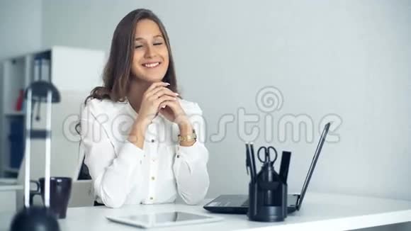 开朗的女商人坐在办公室的桌子旁看着摄像机视频的预览图