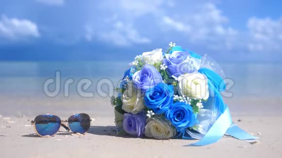 沙滩上美丽的鲜花和太阳镜沙滩上洁白的沙滩海水背景上的热带天堂岛视频的预览图