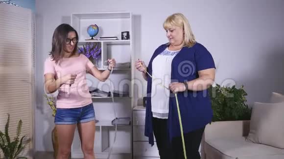 一个胖女人和一个瘦女孩量自己的腰视频的预览图