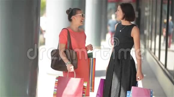 购物的女人说着开心的拿着购物袋开心的笑着两个年轻漂亮的女朋友出差视频的预览图