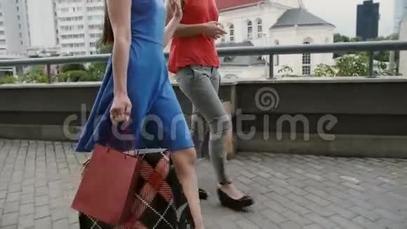 两个年轻漂亮的女朋友拿着购物袋走着谈着玩侧视慢镜头视频的预览图