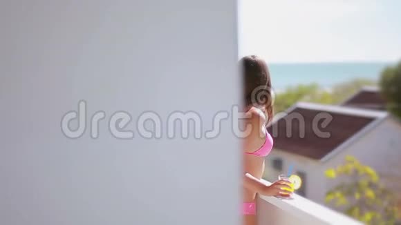 棕色头发的女孩站在度假村的阳台上欣赏海景视频的预览图