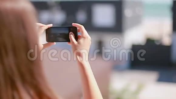 女孩在电话里拍摄现代海滩别墅视频的预览图