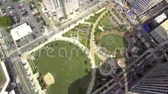 大绿野公园在大现代城市中心繁忙的城市之间的高楼大厦4k空中拍摄的晴天视频的预览图