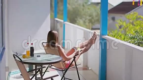 穿着粉红色泳衣的女孩喝完饮料从阳台出去视频的预览图