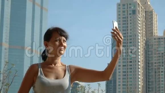微笑的女人在摩天大楼的背景下自拍视频的预览图