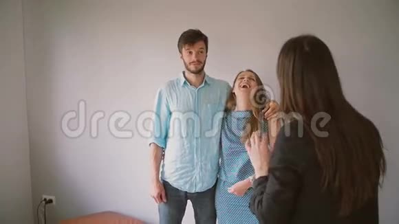 一个年轻漂亮的女人和她的丈夫在听一个穿黑色夹克的女人笑慢动作视频的预览图