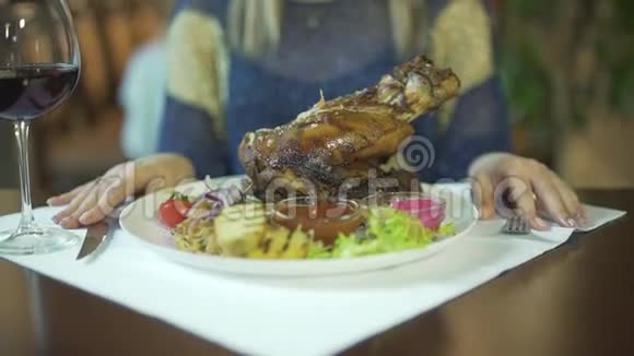 在蔬菜盘子上的一块巨大的烤肉上女人的手在桌子上敲击手指等待着吃视频的预览图