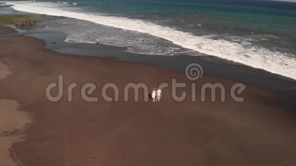 4K航天飞行视频的年轻夫妇在海滩与黑色火山沙在日落时间巴厘岛视频的预览图