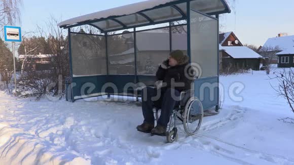 轮椅上的残疾人在公共汽车站附近打电话和检查时间视频的预览图
