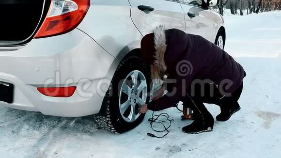 一个女孩正在冬天把轮胎瘪了视频的预览图