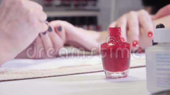 伪装从前景的美甲瓶中蘸取师傅在水疗中心用指甲胶涂清漆特写视频的预览图