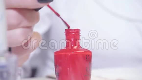 伪装从前景的美甲瓶中蘸取师傅在水疗中心用指甲胶涂清漆特写视频的预览图