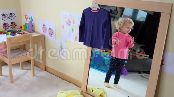 可爱的女孩在家里对着镜子量衣服视频的预览图