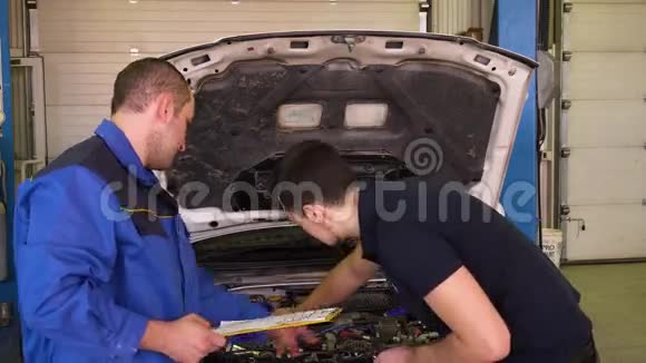 汽车修理工告诉车主需要修理车库里的汽车视频的预览图