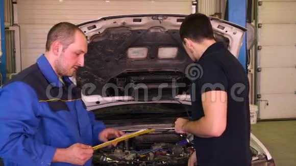 汽车机械师告诉机器主人在车库里修理的情况视频的预览图