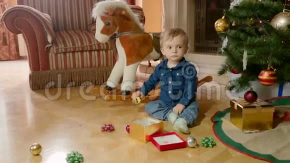 可爱的小男孩在圣诞树下的地板上玩玩具视频的预览图