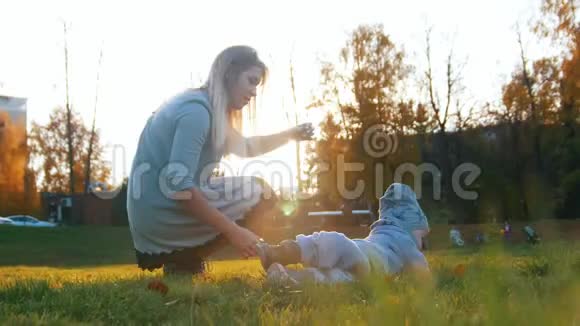 日落时分年轻的妈妈带着一个婴儿在秋天的公园里玩耍视频的预览图