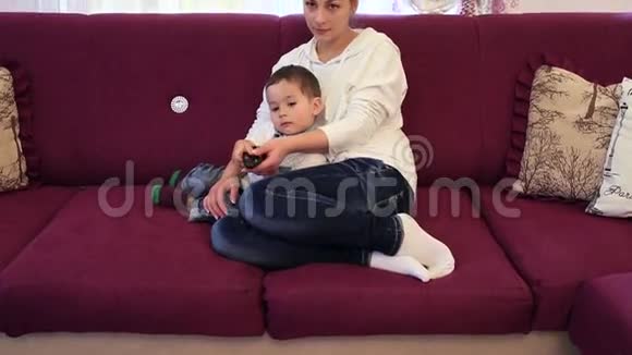 小男孩和他的母亲坐在沙发上看电视视频的预览图