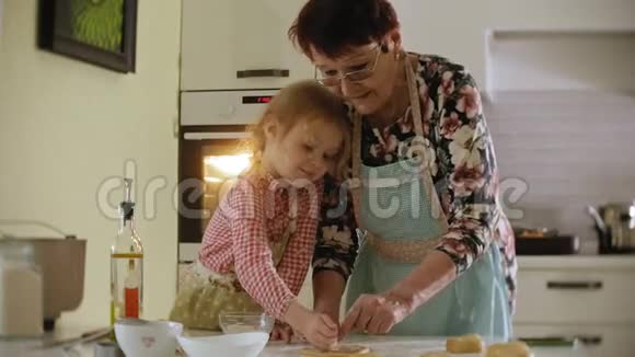 小女孩和奶奶站在厨房里用面团做饼干视频的预览图