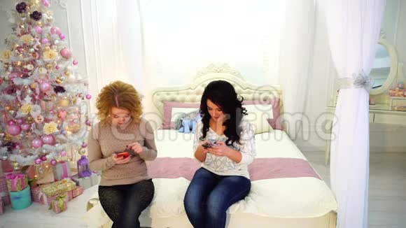 现代女孩使用智能手机做一些私人事情坐在明亮的卧室里铺着节日圣诞树视频的预览图