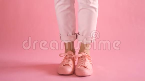 在珊瑚色背景下穿着运动鞋走路的身材匀称的年轻女性腿视频的预览图
