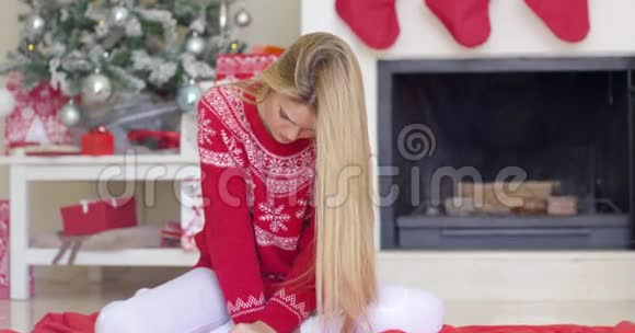 美丽的金发女孩坐在圣诞树旁边视频的预览图