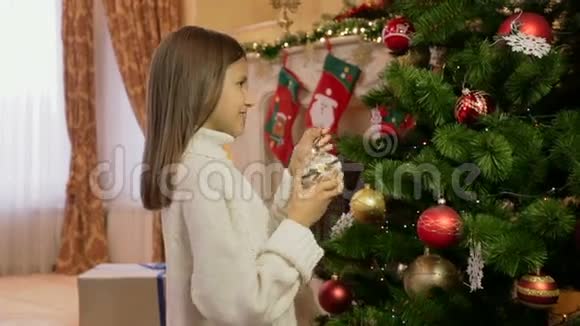 穿白色毛衣的可爱女孩装饰圣诞树的肖像视频的预览图
