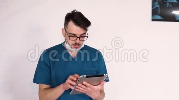 年轻的医生戴着蓝色实验室外套的眼镜分享一个平板电脑特写视频的预览图