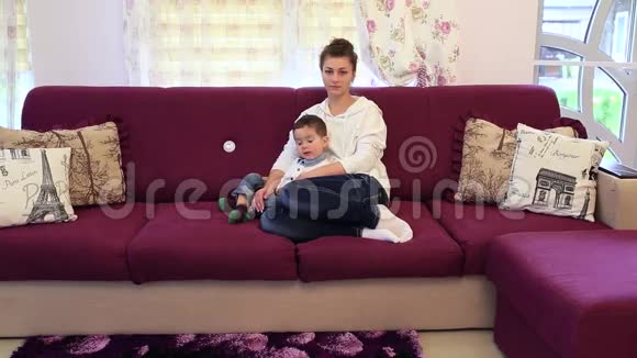 小男孩和他的母亲坐在沙发上看电视视频的预览图