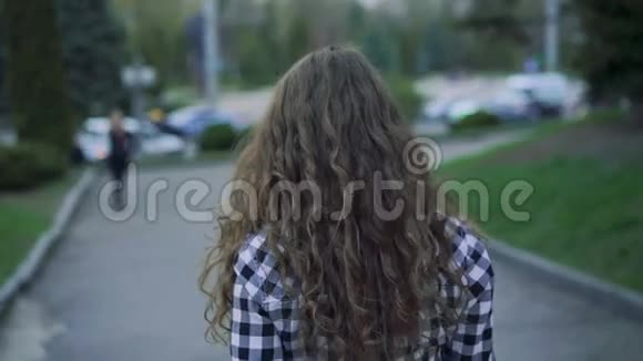 女孩走在街上转身微笑镜头跟在后面慢慢地视频的预览图
