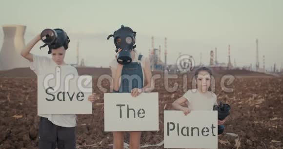 拯救地球带着标牌站在有防毒面具的炼油厂附近的小孩视频的预览图