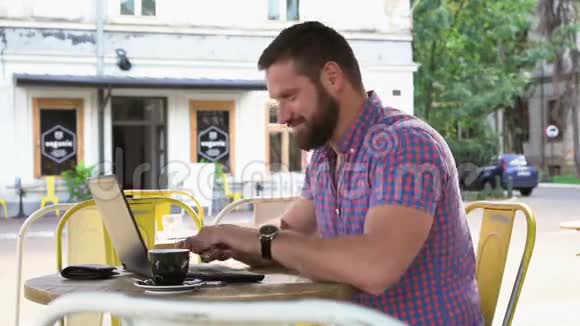 年轻人结束在笔记本电脑上打字在咖啡馆里放松视频的预览图