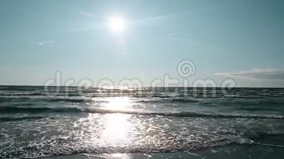 蓝天上明亮的太阳照耀着海面海浪在灯光下闪闪发光视频的预览图