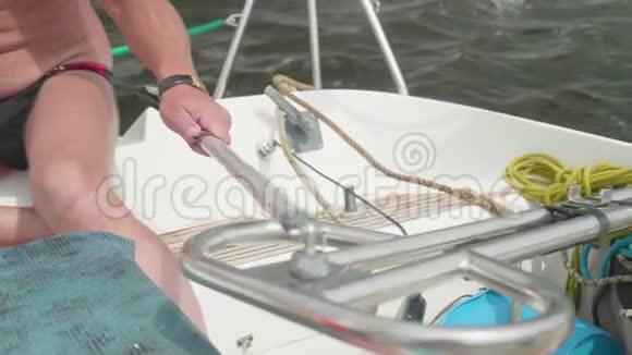 白人男子驾驶一艘带舵柄的白色帆船视频的预览图
