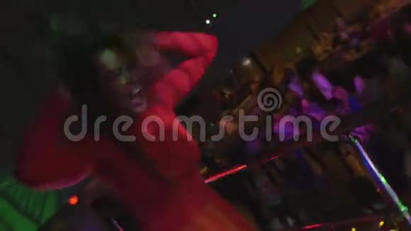 穿红色裙子的女孩在夜总会的派对上站着跳舞聚光灯摇摇头视频的预览图