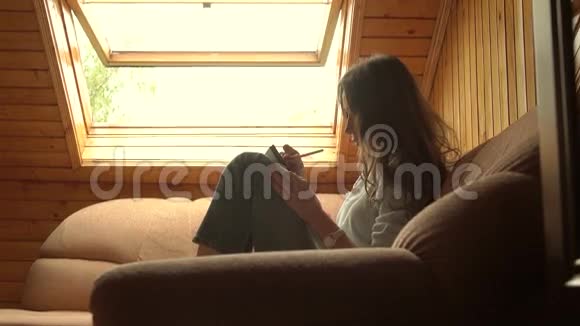 美丽的黑发女孩在大窗户下画画侧写视图4K视频视频的预览图